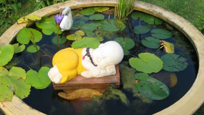 a small ornamental pond in a Thai temple, featuring a reclining novice